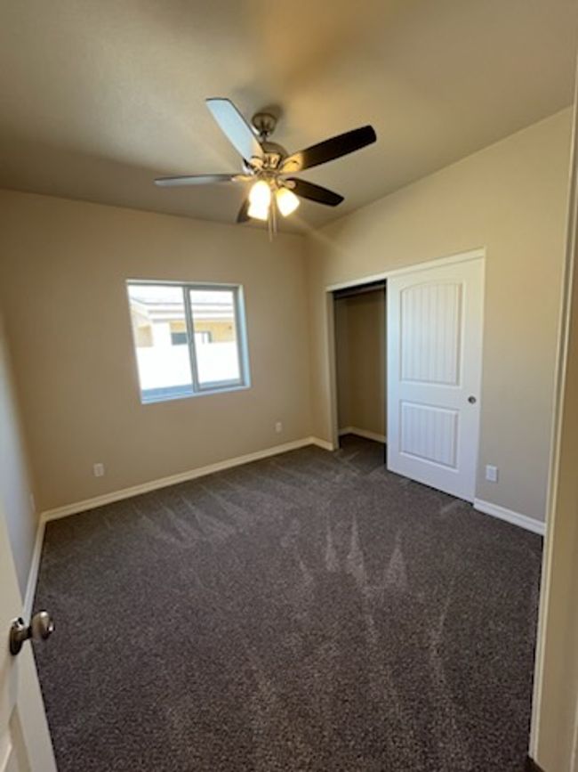 Unfurnished bedroom with baseboards, a closet, dark colored carpet, and ceiling fan | Image 16