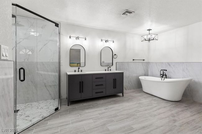 Bathroom featuring a marble finish shower, a textured ceiling, double vanity, and a sink | Image 22