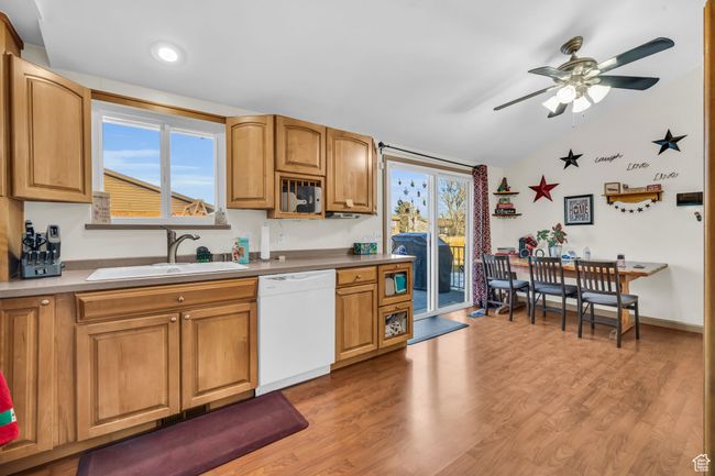 Kitchen featuring dishwasher, ceiling fan, lofted ceiling, a sink, and light wood-type flooring | Image 10