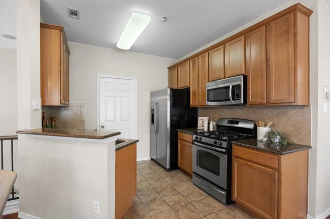 Kitchen featuring stainless steel appliances, granite counter tops, tile flooring, and kitchen bar | Image 11