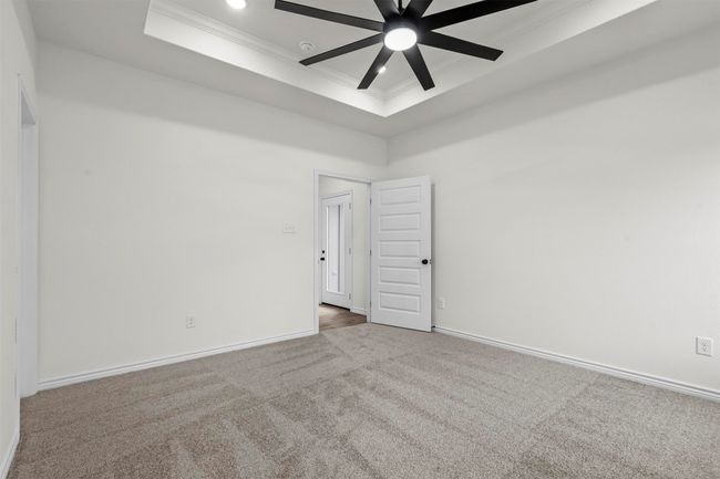 Spare room featuring a tray ceiling, ornamental molding, carpet flooring, and ceiling fan | Image 23
