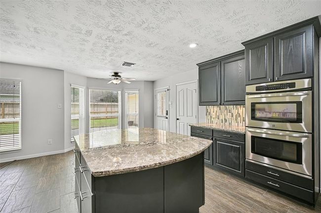 Designed for the home chef, this kitchen features a stainless steel gas cooktop with a built-in vent hood microwave, double wall ovens, a dual basin sink, and a generous walk-in pantry. | Image 14