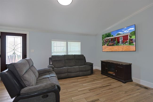 Living room with crown molding, baseboards, visible vents, and light wood finished floors | Image 11