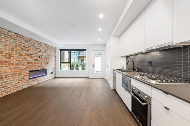 Kitchen with stainless steel appliances, dark countertops, white cabinets, dark wood-style floors, and tasteful backsplash | Image 18