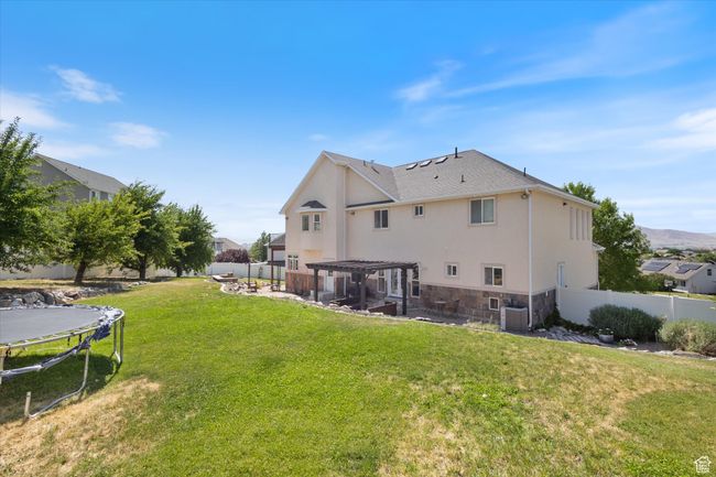 Rear view of house featuring a patio area, a pergola, a fenced backyard, and stone siding | Image 29