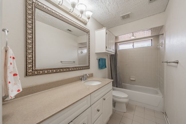 Bathroom featuring shower / bathtub combination, vanity, a textured ceiling, and tile patterned flooring | Image 17