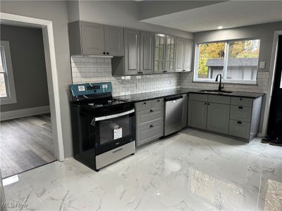 Kitchen featuring new gray cabinetry, granite counters, subway tile backsplash, new stainless steel appliances and ceramic tile floors. | Image 2