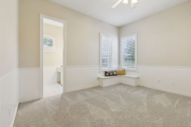 Split secondary bedroom boasts new carpet, plantation shutters, walk-in closet with built-ins, beadboard, ceiling fan, window seat and en suite jack and jill bathroom | Image 26