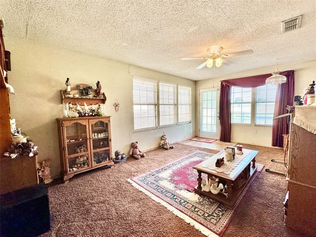 Carpeted living area with a ceiling fan and a textured ceiling | Image 25