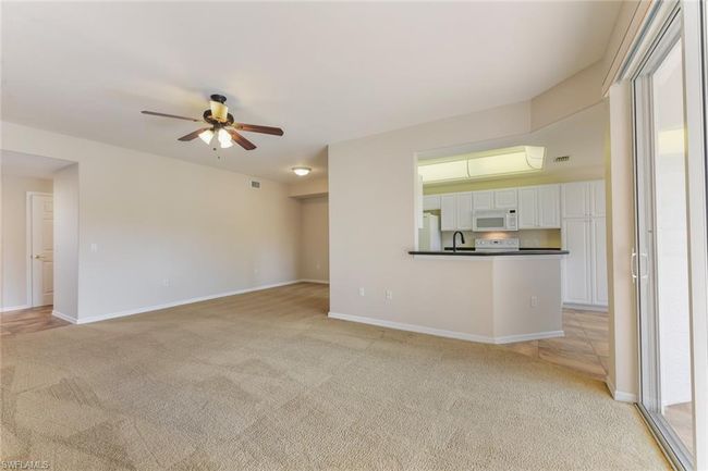 Unfurnished living room with light carpet, baseboards, a sink, and a ceiling fan | Image 13