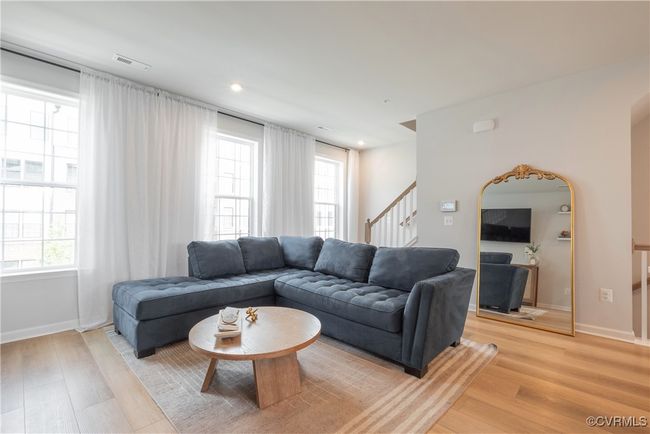 Living area featuring visible vents, light wood-style floors, stairs, and a healthy amount of sunlight | Image 15