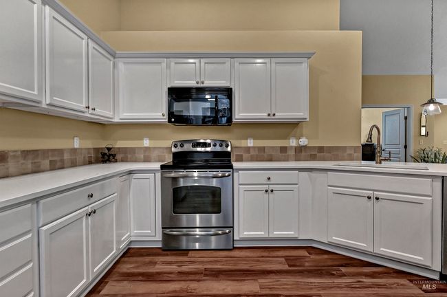 Kitchen featuring black microwave, stainless steel electric stove, light countertops, and white cabinets | Image 14