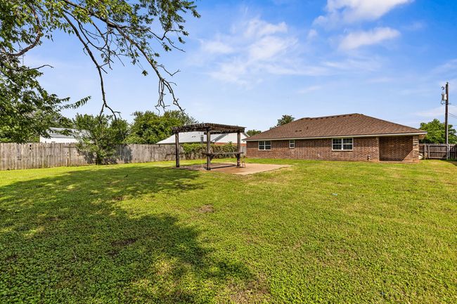 Fenced backyard with a pergola and a patio area | Image 10