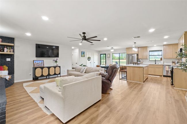 Living room with a brick fireplace, recessed lighting, light wood-type flooring, and ceiling fan | Image 10