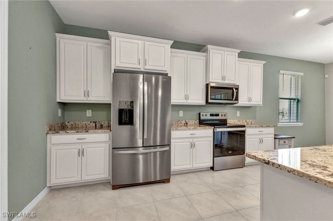 Kitchen featuring light stone countertops, white cabinetry, visible vents, and stainless steel appliances | Image 26