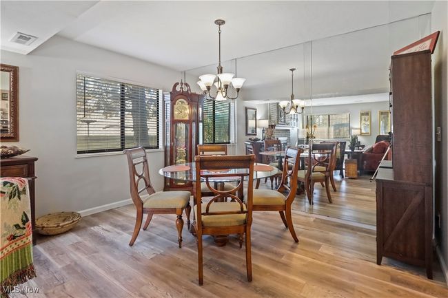Dining room featuring visible vents, light wood-style floors, a notable chandelier, and baseboards | Image 6