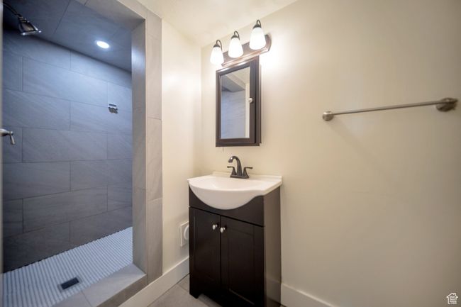 Bathroom with tile patterned flooring, a tile shower, and vanity | Image 10