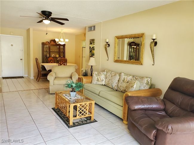 Living area featuring ceiling fan with notable chandelier, visible vents, and light tile patterned floors | Image 7