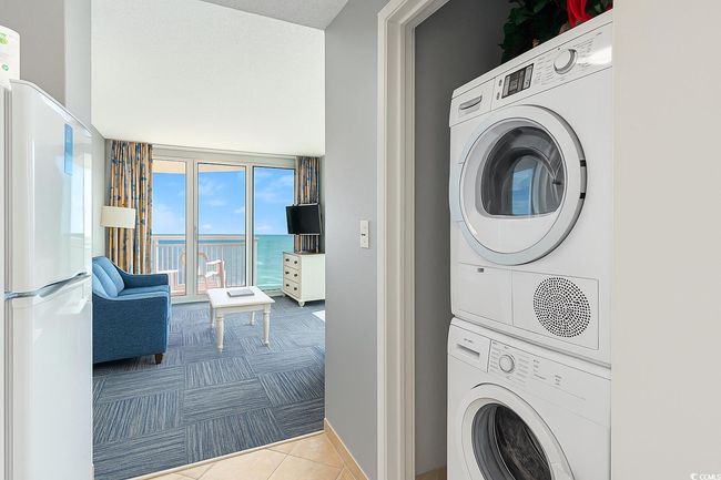 Washroom featuring stacked washer / dryer, carpet flooring, baseboards, and tile patterned floors | Image 11