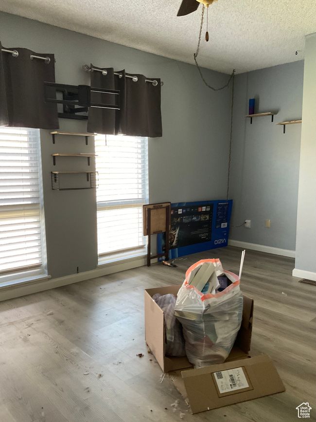 Living room with ceiling fan, baseboards, wood finished floors, and a textured ceiling | Image 9