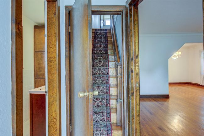 Hallway with wood finished floors, stairs, a chandelier, and ornamental molding | Image 21