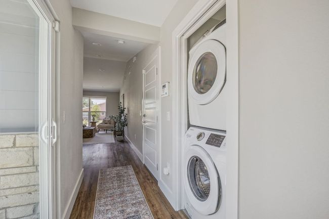 Laundry room featuring stacked washer and clothes dryer and dark wood finished floors | Image 17