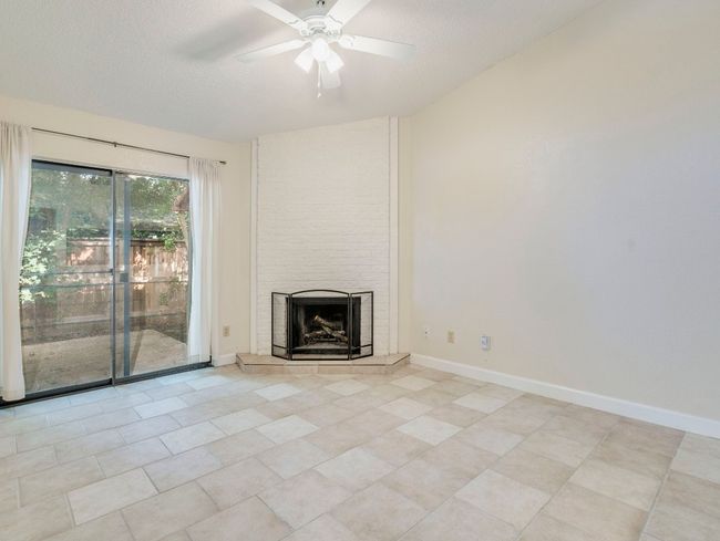 Unfurnished living room with a tiled fireplace, ceiling fan, baseboards, and light tile patterned floors | Image 4