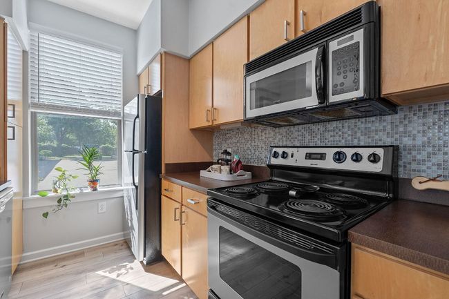 Kitchen featuring stainless steel appliances, dark countertops, tasteful backsplash, and light wood-style floors | Image 5