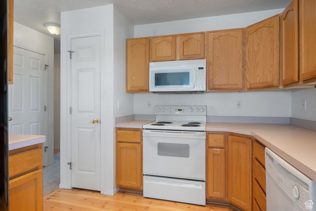 Kitchen featuring white appliances, light wood-type flooring, and light countertops | Image 12