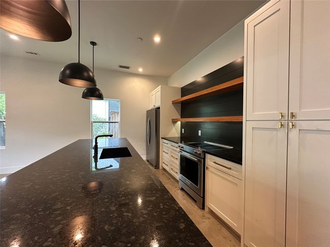 Kitchen featuring stainless steel appliances, open shelves, white cabinets, recessed lighting, and hanging light fixtures | Image 25