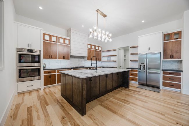 Kitchen with glass insert cabinets, dark brown cabinets, decorative light fixtures, tasteful backsplash, and recessed lighting | Image 7