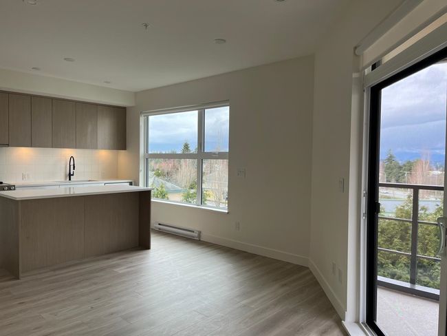 Kitchen with light countertops, backsplash, modern cabinets, baseboard heating, and light wood-style floors | Image 8