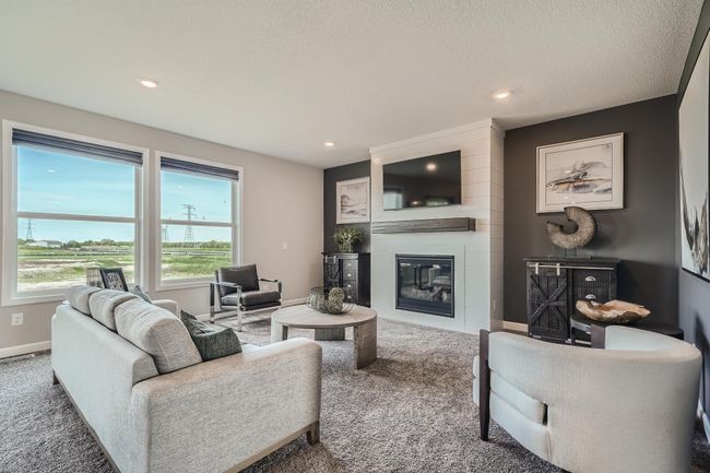 Photo is of the model. Spacious great room with an abundance of natural light and a fireplace. | Image 7