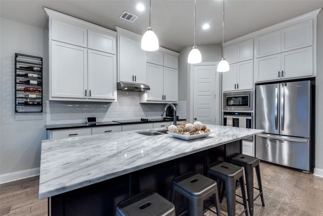 Kitchen featuring baseboards, appliances with stainless steel finishes, a sink, and visible vents | Image 8