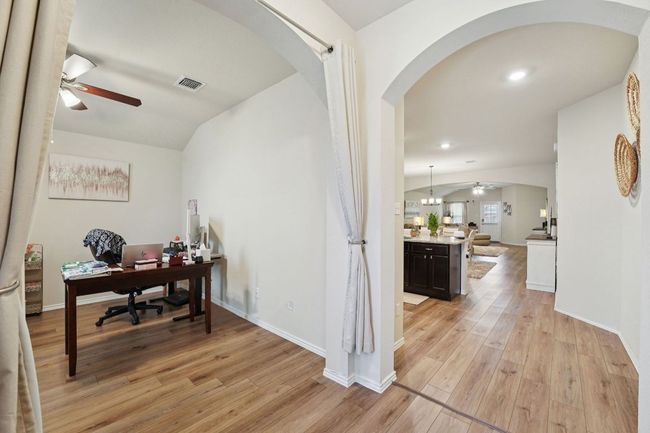 Office with a ceiling fan, arched walkways, light wood finished floors, and lofted ceiling | Image 26