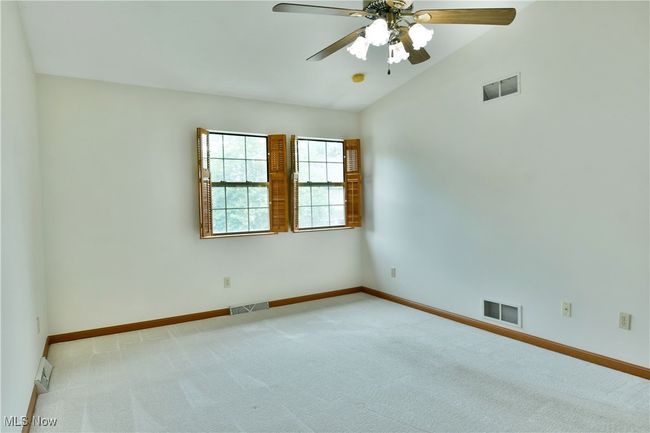 Carpeted spare room featuring ceiling fan and vaulted ceiling | Image 36