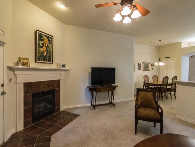 Living area featuring ceiling fan, a tile fireplace, dark carpet, and baseboards | Image 17