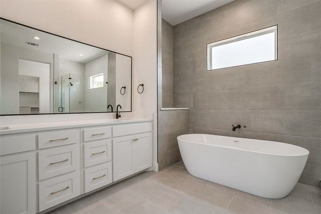 Full bath featuring double vanity, plenty of natural light, a freestanding bath, and a stall shower | Image 24