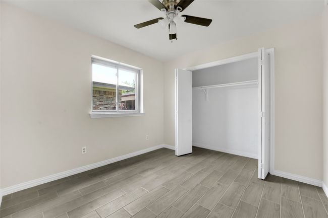 Unfurnished bedroom with wood finish floors, a closet, and a ceiling fan | Image 11