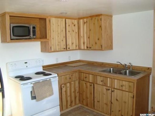 Kitchen featuring electric range, light tile patterned flooring, sink, and light brown cabinetry | Image 42