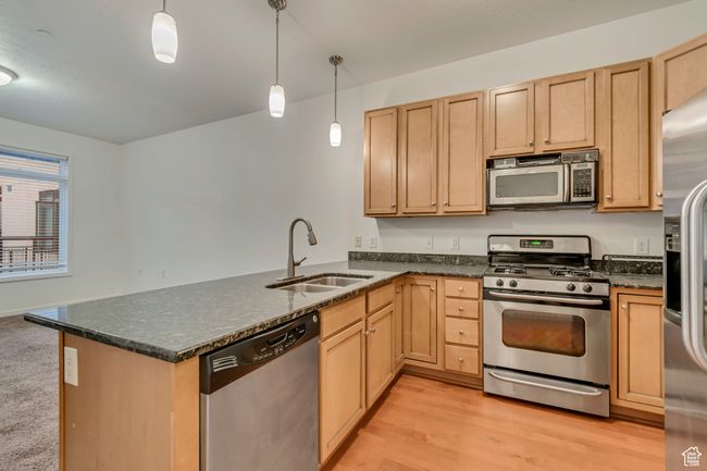 Kitchen with stainless steel appliances, light brown cabinetry, a sink, light wood-style floors, and a peninsula | Image 11