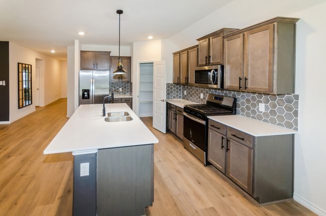 Kitchen featuring appliances with stainless steel finishes, a sink, light wood-style floors, light countertops, and recessed lighting | Image 5