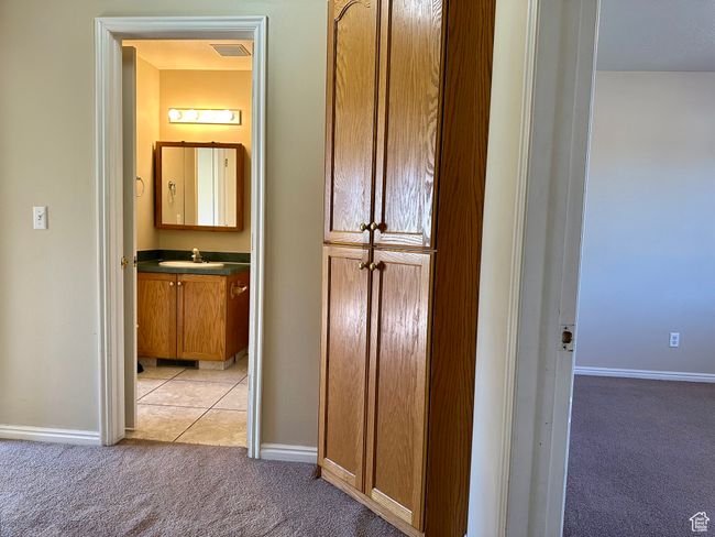 Hall with light colored carpet and light tile patterned flooring built-in storage cabinet | Image 12