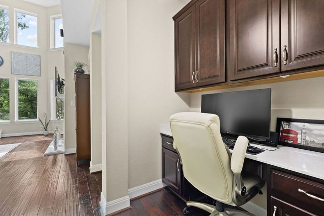 Office space with dark wood-type flooring, built in study area, and baseboards | Image 19