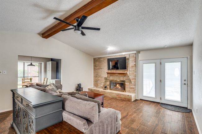 Living room with dark wood-type flooring, a ceiling fan, a textured ceiling, and a fireplace | Image 5