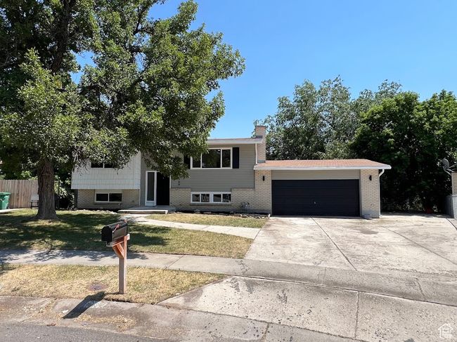 View of front facade featuring an attached garage, driveway, a chimney, and brick siding | Image 28