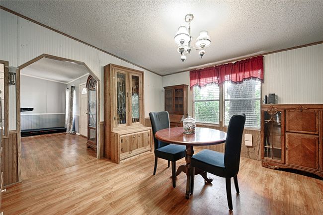 Dining space with wainscoting, arched walkways, wooden walls, crown molding, and light wood-type flooring | Image 15