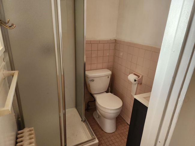 Full bath featuring vanity, a stall shower, tile patterned flooring, a wainscoted wall, and tile walls | Image 4