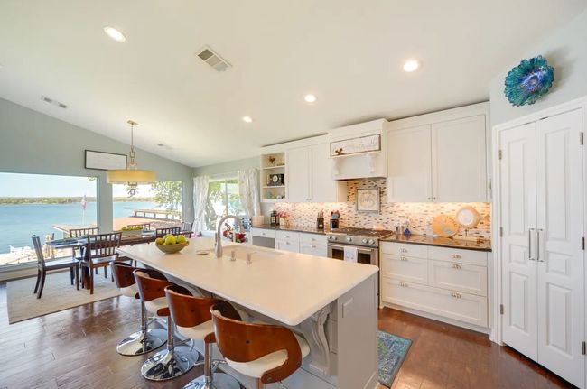 Kitchen with lofted ceiling, white cabinetry, high end range, dark wood finished floors, and backsplash | Image 5