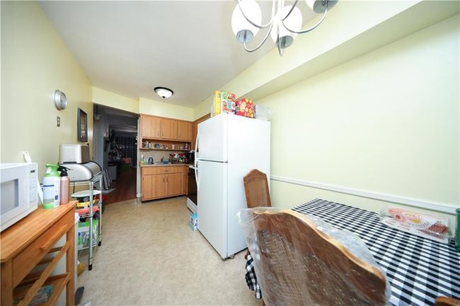 Kitchen with white appliances, a chandelier, light carpet, and light countertops | Image 12
